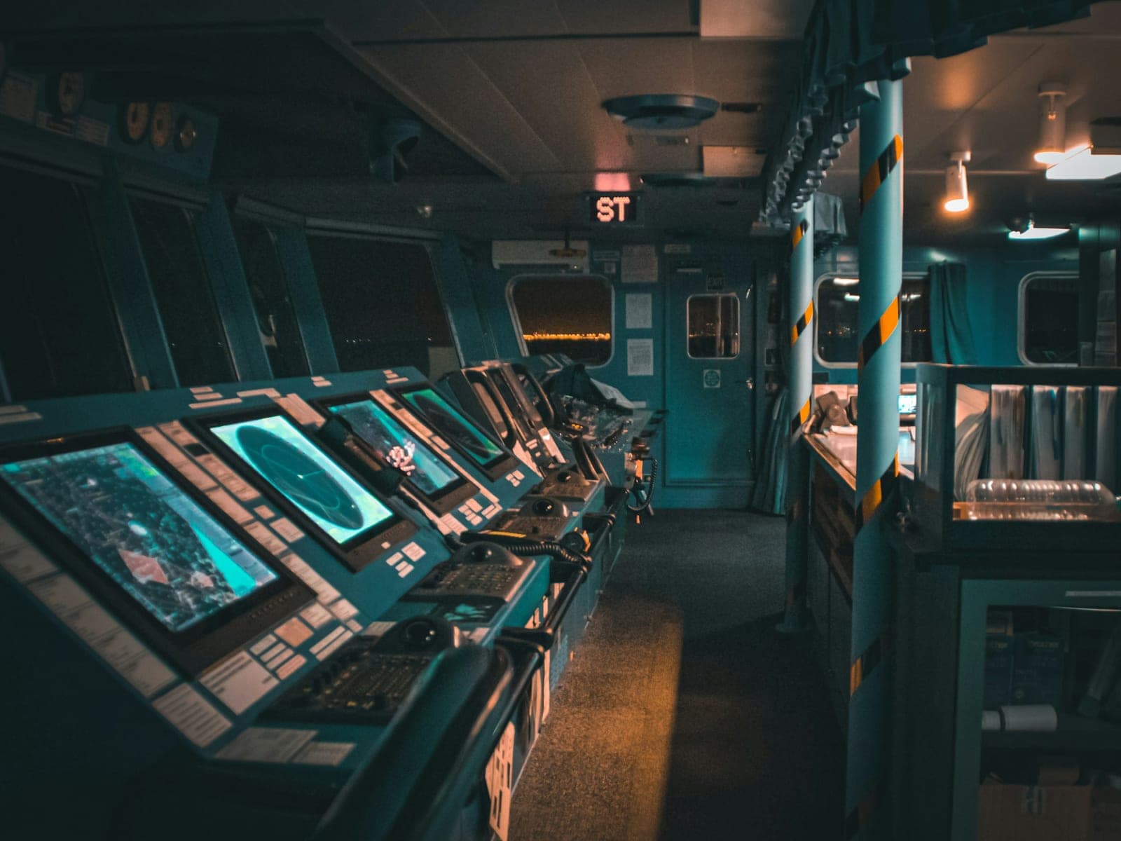Dim ship bridge at night with a row of consoles, one display showing a circular radar sweep
