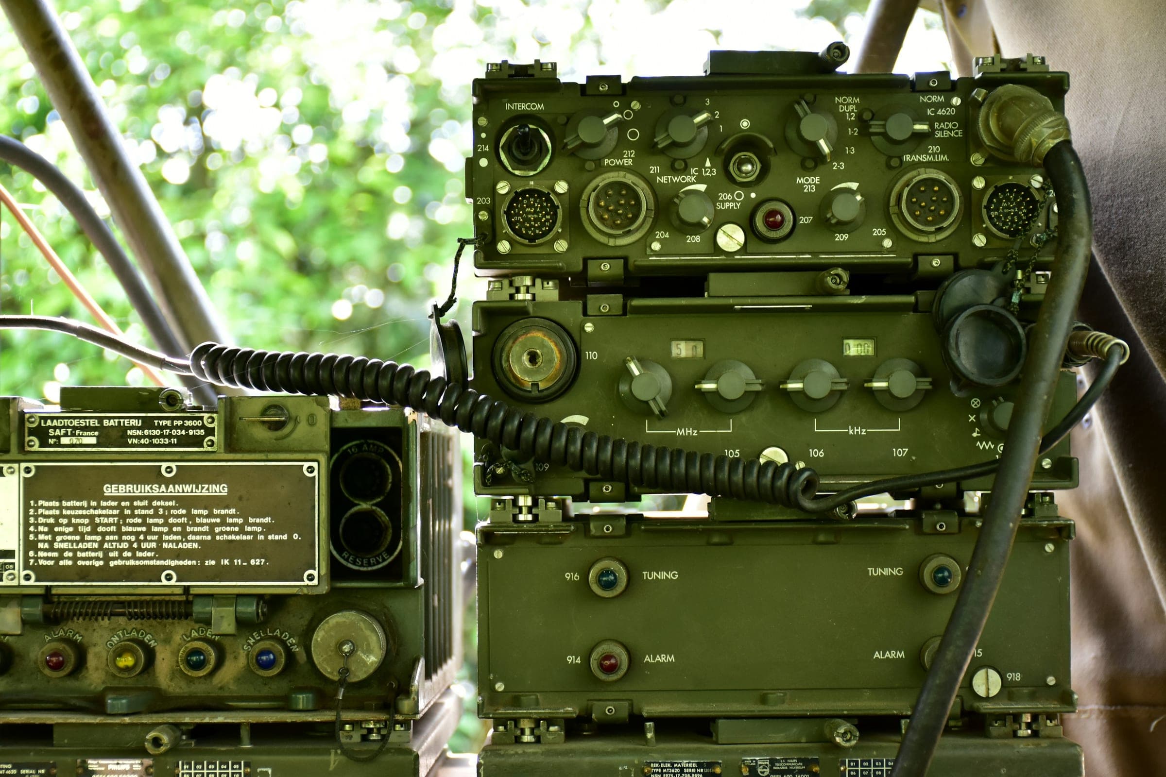 Stacked olive-green field radio sets with coiled handset cables